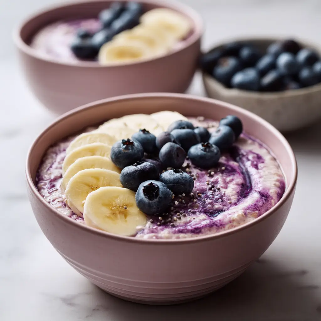 The simple ingredients for blueberry banana overnight oats, including rolled oats, a banana, blueberries, and milk, arranged on a bright surface.