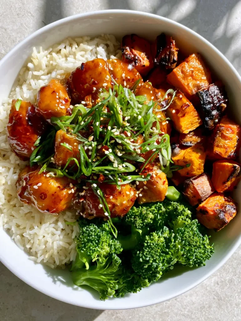 Close-up shot highlighting glossy hot honey pan-seared chicken breast pieces covered in red chili flakes and sesame seeds.