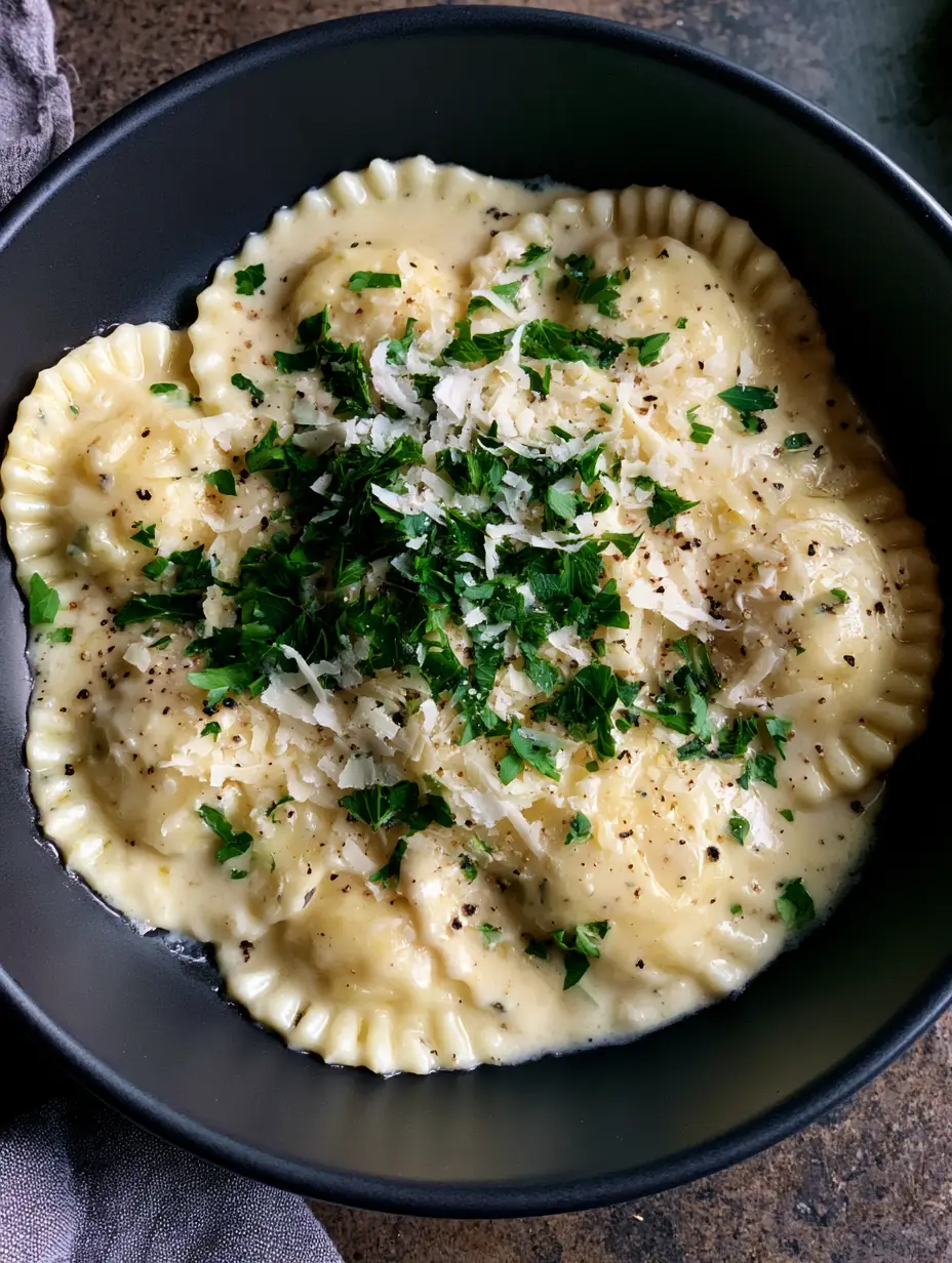 Creamy Garlic Parmesan Ravioli with Fresh Parsley 3 A close-up shot of round scalloped cheese ravioli drenched in ivory garlic cream sauce. (Creamy Garlic Parmesan Ravioli)